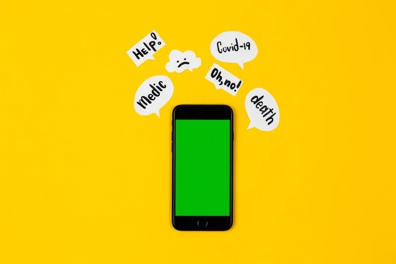 Creative concept of coronavirus mockup. A black telephone lies on a yellow background, next to it are paper message clouds on which the inscriptions associated with the covid-19 virus are written
